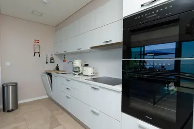 a kitchen with white cabinets and a black oven at Elísio do Mar by LovelyStay in Prazeres