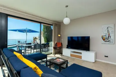 a living room with a blue couch and a tv at Elísio do Mar by LovelyStay in Prazeres