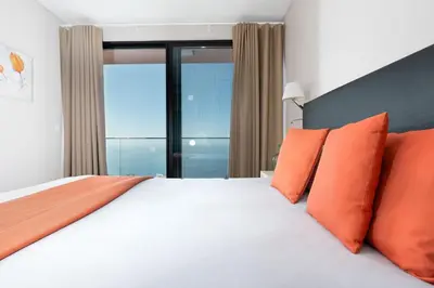 a bedroom with a large bed with orange pillows at Elísio do Mar by LovelyStay in Prazeres