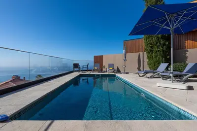 a swimming pool with chairs and an umbrella on a building at Elísio do Mar by LovelyStay in Prazeres