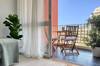 a room with a balcony with a chair and a table at Blue Wave, a Home in Madeira in Funchal