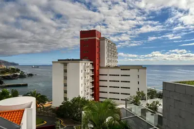 a red and white building with the ocean in the background at Blue Wave, a Home in Madeira in Funchal