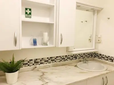 a white bathroom with a sink and a mirror at Apartment Banana Panorama: central Lido area in Funchal