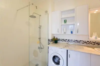a washing machine in a bathroom with a shower at Apartment Banana Panorama: central Lido area in Funchal