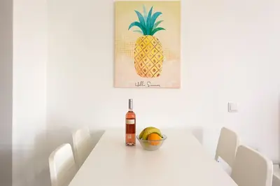 a white table with a bottle of wine and a bowl of fruit at Apartment Banana Panorama: central Lido area in Funchal