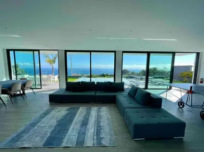 a large living room with a couch and a table at Panoramic View: Lux 3 bed with heated pool in Arco da Calheta