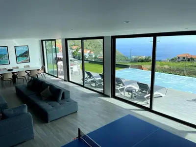 a living room with a view of a swimming pool at Panoramic View: Lux 3 bed with heated pool in Arco da Calheta