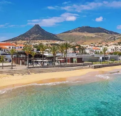 a living room with a blue couch and a kitchen at SandyBeachApartment in Porto Santo