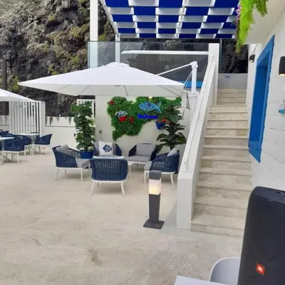 a patio with chairs and an umbrella and stairs at Mediterrâneo Madeira in São Vicente