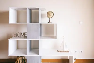 a white book shelf in a living room with a clock at By the Sea II - calmo com piscina e vista mar. in Funchal