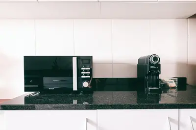 a kitchen counter with a microwave and a coffee maker at By the Sea II - calmo com piscina e vista mar. in Funchal
