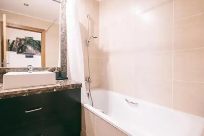 a bathroom with a tub and a sink and a mirror at By the Sea II - calmo com piscina e vista mar. in Funchal