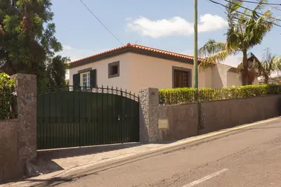 a white house with a black gate on a street at Pilar House in Funchal