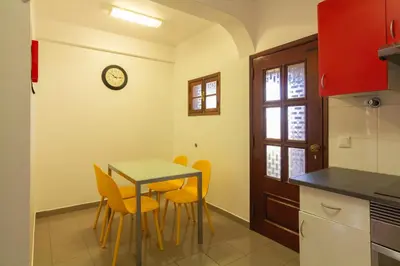 a kitchen with a table and chairs and a clock on the wall at Pilar House in Funchal
