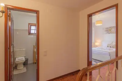 a bathroom with a toilet and a hallway with a staircase at Pilar House in Funchal