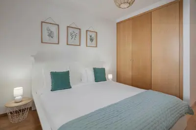 a bedroom with a white bed and a wooden cabinet at Ribeira Brava I by An Island Apart in Ribeira Brava
