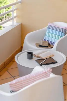 a white chair with a table with a hat and a book at Ajuda IV by An Island Apart in Funchal