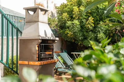 a outdoor pizza oven next to a green railing at Melro's Place by Stay Madeira in Ponta do Sol