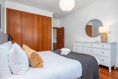 a bedroom with a white bed with a dresser and a mirror at Ficcus Home in Caniço