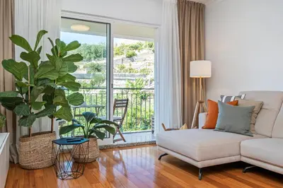 a living room with a couch and a large window at Ficcus Home in Caniço