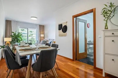 a dining room and living room with a table and chairs at Ficcus Home in Caniço