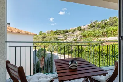 a balcony with a wooden table and a view of the ocean at Ficcus Home in Caniço