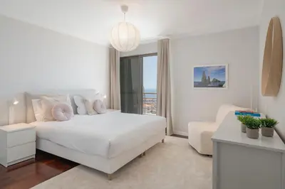 a white bedroom with a white bed and a window at Caniço VII by An Island Apart in Santa Cruz