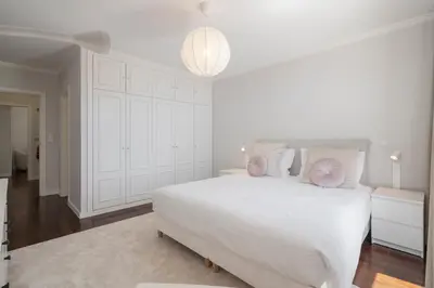 a white bedroom with a large white bed with pink pillows at Caniço VII by An Island Apart in Santa Cruz