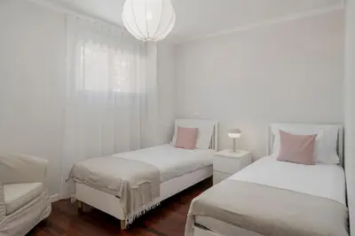 a white bedroom with two beds and a couch at Caniço VII by An Island Apart in Santa Cruz