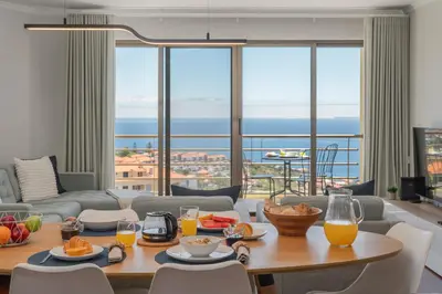 a living room with a table with food and orange juice at Caniço VII by An Island Apart in Santa Cruz