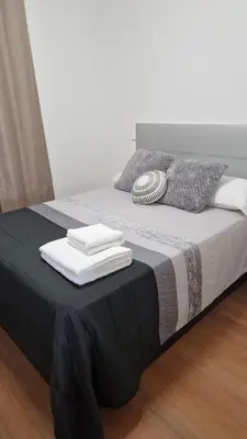 a bed with a black and white blanket and pillows at Vila Henrique Country Cottage in Fajã da Ovelha