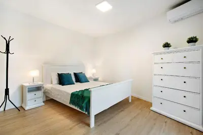 a bedroom with a white bed and a white dresser at Casa Fonte São João in Vila Baleira