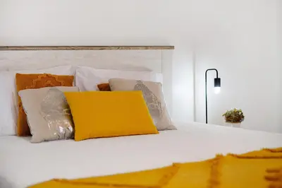 a white bed with pillows and a yellow pillow at Casa Fonte São João in Vila Baleira