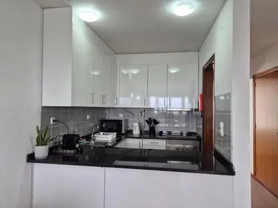 a kitchen with white cabinets and a black counter top at Machico Terrace in Machico