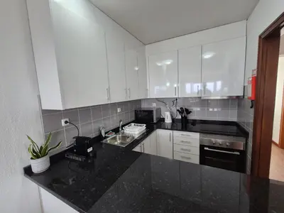a kitchen with white cabinets and a black counter top at Machico Terrace in Machico
