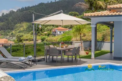 a table with an umbrella next to a swimming pool at OurMadeira - This Side of Paradise in Arco da Calheta