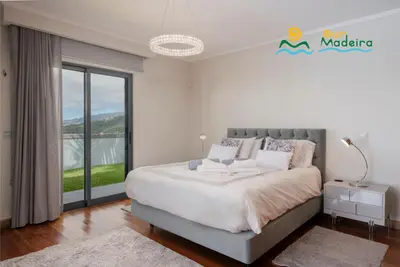 a bedroom with a large bed and a large window at OurMadeira - This Side of Paradise in Arco da Calheta