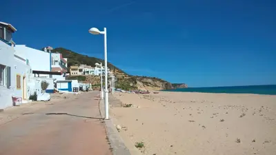 a street light on a beach next to the ocean at Casa Sereia Praia in Salema