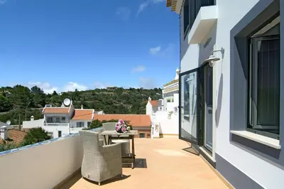 a balcony with a table and chairs on a building at Casa Sereia Praia in Salema