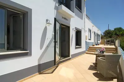 a balcony of a house with a table and flowers at Casa Sereia Praia in Salema