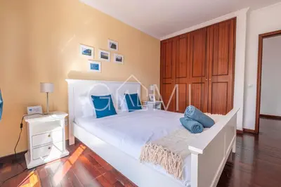 a bedroom with a large white bed with blue pillows at Casa Vista Mar by GALMI in Calheta