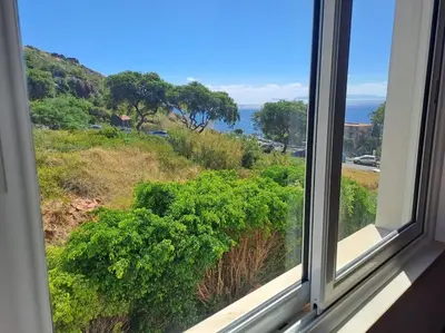 a window with a view of a field of bushes at Ocean Gardens in Caniço