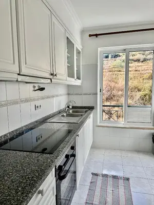 a white kitchen with a sink and a window at Ocean Gardens in Caniço