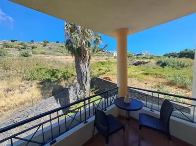 a balcony with a table and chairs and a palm tree at Ocean Gardens in Caniço