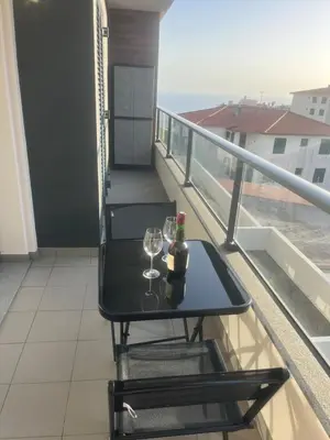 a balcony with a table and two glasses of wine at Paradise Garajau in Garajau