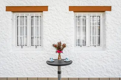 a table in front of a building with two windows at Sweet Home Madeira in Camacha