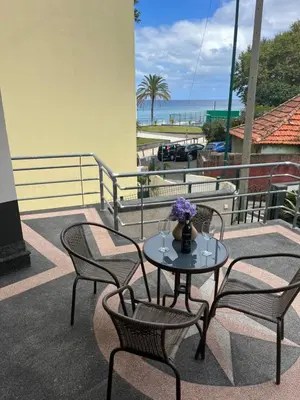 a table and chairs on a balcony with the ocean at Vivenda da Praia in Machico