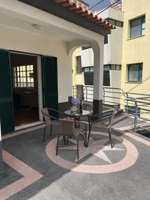 a patio with a table and chairs in front of a building at Vivenda da Praia in Machico