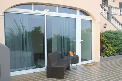a balcony with glass doors with a chair and a table at Lugar dos Louros 1 in Estreito da Calheta
