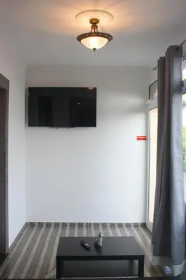 a living room with a table and a tv on a wall at Lugar dos Louros 1 in Estreito da Calheta
